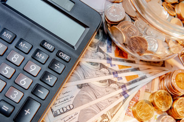 Wall Mural - Calculator with currency glass jar and gold coins stack, dollar and euro banknotes on the table. Compound interest rate calculation or financial investment business concepts