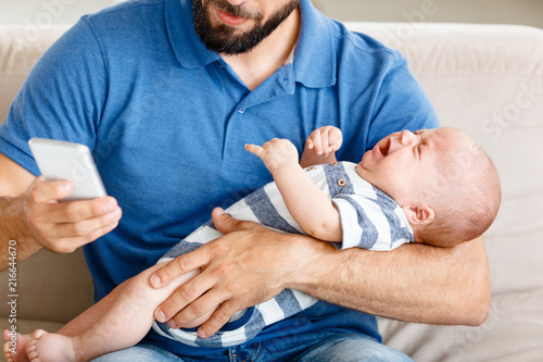 Father Holding Crying Baby Boy And Using Smart Phone Stock Photo Adobe Stock