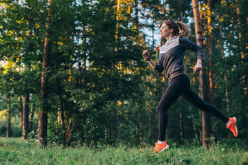 Portrait of young female athlete wearing tracksuit running in forest