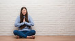 © Krakenimages.com - Young Chinese woman sitting on the floor over brick wall begging and praying with hands together with hope expression on face very emotional and worried. Asking for forgiveness. Religion concept.