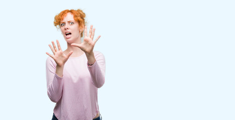 Canvas Print - Young redhead woman afraid and terrified with fear expression stop gesture with hands, shouting in shock. Panic concept.