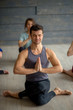 Young sportive male instructor practicing yoga with group of young women in studio over grey background. Training, Flexibility, Well-being Concept
