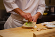 Professional sushi chef is using Oroshigane to grate fresh root of Wasabi or Japanese horseradish. Oroshigane or oroshiki is a Japanese style hand grater with the surface made from shark skin.
