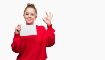 Sticker - Young blonde woman holding advertising banner doing ok sign with fingers, excellent symbol