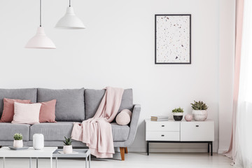 Wall Mural - Poster above cabinet with plants in white flat interior with pink blanket on grey couch. Real photo
