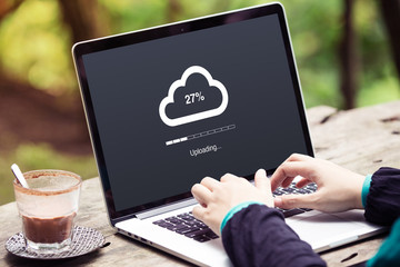 Woman doing cloud uploading on laptop / computer at the park / outdoor