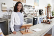 © Monkey Business - Female coffee shop owner standing smiling behind the counter
