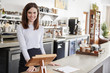 © Monkey Business - Young female coffee shop owner behind the counter, smiling