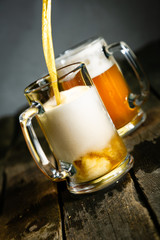 Canvas Print - Pouring beer in glasses on rustic background