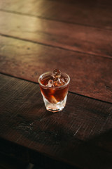 Wall Mural - Cold brew coffee with ice cubes in glass on the wooden table from above. Urban coffee shop. Vertical, copyspace