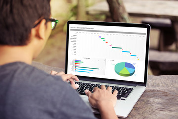 Man working with excel project dashboard on laptop / computer at the park / outdoor