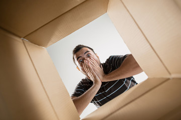 The surprised man unpacking, opening carton box and looking inside. The package, delivery, surprise, gift lifestyle concept