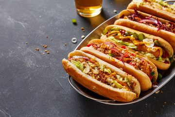 Wall Mural - Hot dogs fully loaded with assorted toppings on a tray.