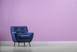Stylish comfortable armchair near color wall