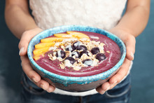 Woman holding bowl with tasty acai smoothie, closeup