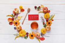 Apples, Honey, Plums, Red Berries And Beautiful Flowers  With Copy Space Form A Floral Decoration.  Summer And Autumn Concept.  Top View, Close Up On White  Wooden Background.