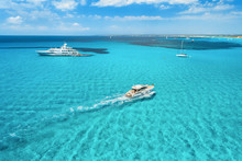 Yacht On The Azure Seashore In Balearic Islands. Aerial View Of Floating Boat With People In Transparent Sea At Sunny Day In Summer. Top View From Drone. Seascape With Luxury Yachts In Motion In Bay