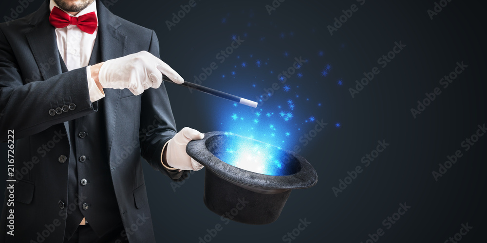 Magician or illusionist is showing magic trick with wand and hat on dark background. - obrazy, fototapety, plakaty 