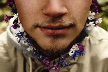 stylish blonde hipster with beard with flowers on the background of mountains