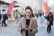 © contrastwerkstatt - Young cheerful woman wearing grey coat using phone