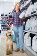 © caftor - female with Afghan Shepherd puppy choose pet food in zoo store