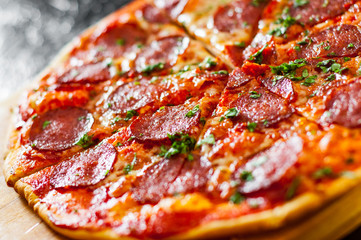 sliced Pepperoni Pizza with Mozzarella cheese, salami, Tomatoes, pepper, Spices and Fresh Basil. Italian pizza