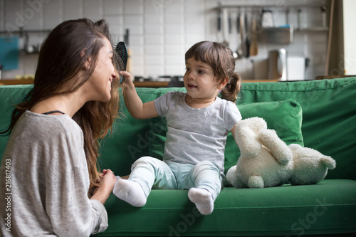 Cute Kid Girl Brushing Mothers Hair Having Fun Together On