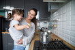 © fizkes - Smiling mom holding cute kid girl hepling mum in the kitchen, happy family of young single mother and daughter talking having fun cooking together, happy mommy teaching child preparing food