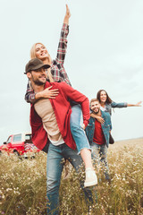 Wall Mural - young women piggybacking on boyfriends in flower field