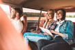 © LIGHTFIELD STUDIOS - young group of friends sitting in car while having trip