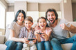 © estradaanton - Amazing family sits on sofa. Children are playing on xbox. The game is intense. Guy rejoys. Girl is smiling as well. Mother helps to play her son.