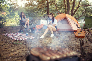 Party, camping of men and women group at forest. They relaxing, singing a song and cooking barbecue against green grass. The vacation, summer, adventure, lifestyle, picnic concept