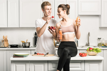 Wall Mural - boyfriend feeding girlfriend with organic strawberries in kitchen