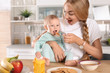 Woman feeding her child in kitchen. Healthy baby food