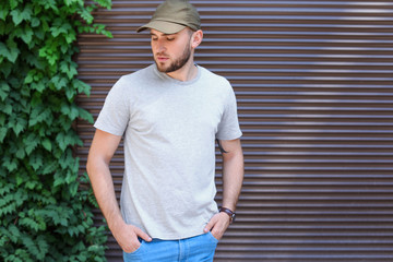 Wall Mural - Young man wearing gray t-shirt near wall on street. Urban style