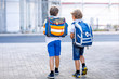 © Irina Schmidt - Two little kid boys with backpack or satchel. Schoolkids on the way to school. Healthy adorable children, brothers and best friends outdoors on the street leaving home. Back to school. Happy siblings.