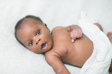 awake newborn baby on cream white background