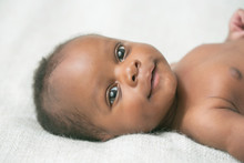 Smiling Awake Newborn Baby On Cream White Background