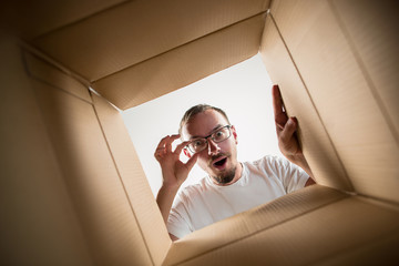 the surprised man unpacking, opening carton box and looking inside. the package, delivery, surprise,