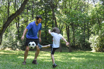 Wall Mural - Father and son play with ball in autumn park. Happy family play soccer in public park