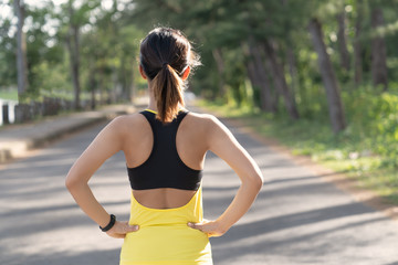 Wall Mural - Back view of young fitness woman running on the road in the morning, People and sport concept, Selective focus