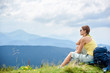 © anatoliy_gleb - Back view of attractive woman tourist sitting and resting on grassy hill with backpack. Female backpacker enjoying summer cloudy day in the Carpathian mountains. Outdoor activity, tourism concept