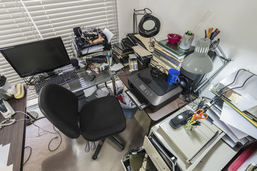 Messy office desk with stacks of files and disorganized clutter.