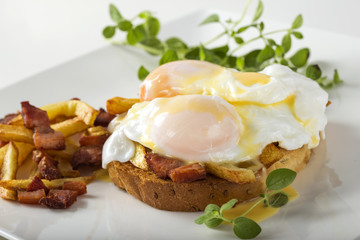 toast sandwich with two poached eggs, french fries and bacon