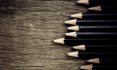 black pencil on old wooden desk. - vintage backdrop style.