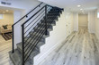 © Javani LLC - Empty white hallway with grey hardwood floor and a staircase.
