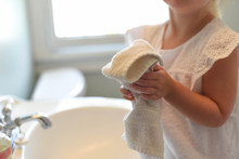 Little girl drying hands on a towel in bright morning light