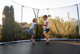 Fototapeta Miasto - Little kids bouncing off the trampoline taut