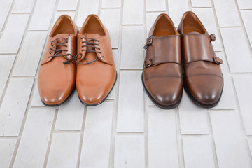 mans fashion two leather shoes on white brick wall