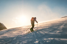 Man Skier With Backpack Trekking On Snow Mountain With Sunlight